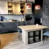 Stół do salonu z aneksem – na co dzień kompaktowa wyspa kuchenna, a po rozłożeniu duży stół jadalniany. Mechanizm poprzeczny, 3 wkładki w nodze, opcjonalna witrynka z przeszklonymi drzwiczkami.