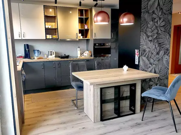 Stół do salonu z aneksem – na co dzień kompaktowa wyspa kuchenna, a po rozłożeniu duży stół jadalniany. Mechanizm poprzeczny, 3 wkładki w nodze, opcjonalna witrynka z przeszklonymi drzwiczkami.